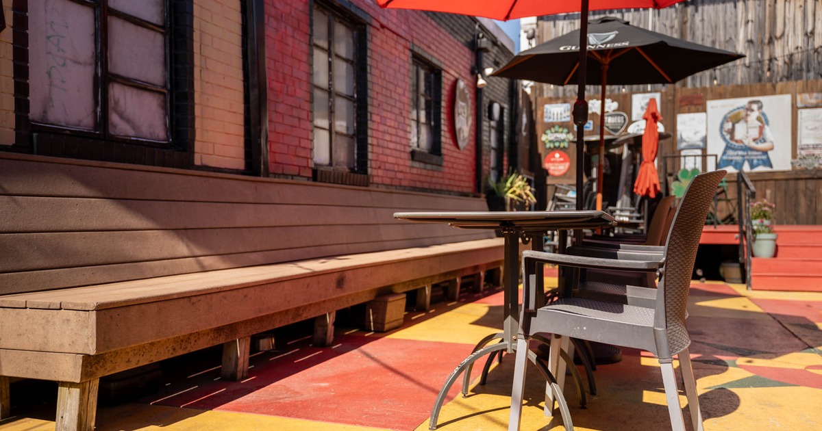 Exterior, partially covered seating area, long banquette bench with tables and chairs