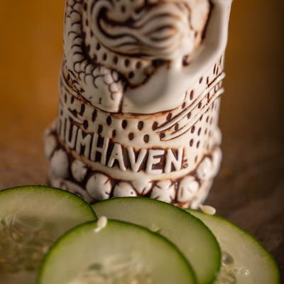 Cucumber slices placed in front of a mermaid mug, closeup