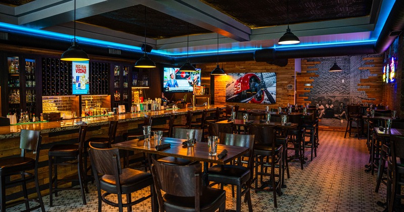 Interior - wooden furnishings, a long counter, pendant lights, TV screens and decorative murals.
