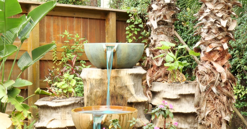 Outside, a Garden fountain among plants and palms
