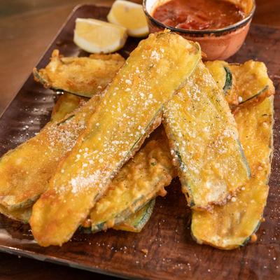 Fried zucchini served with lemon wedges and marinara sauce.