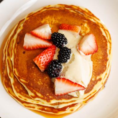 Pancakes topped with strawberries, blackberries, and cream.