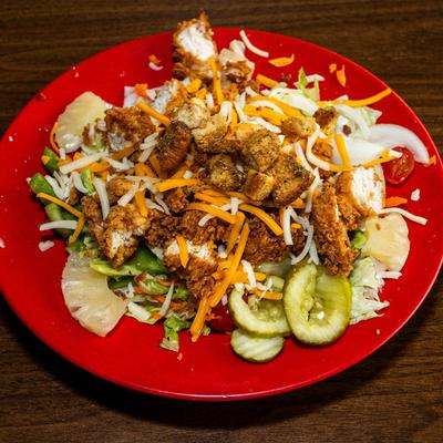Salad topped with crispy chicken, cheese, croutons, lettuce, pickles, and pineapple.
