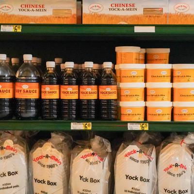 Shelves filled with sauces in bottles and containers and packaged noodles.