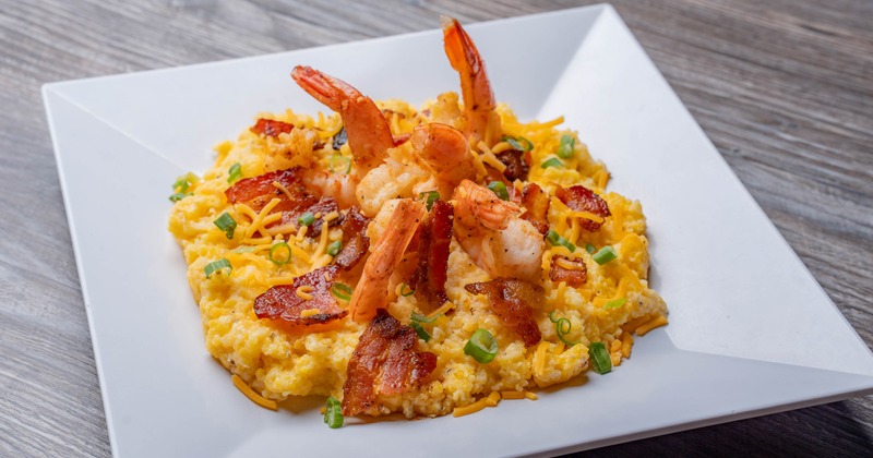 Shrimp and grits topped with bacon and herbs