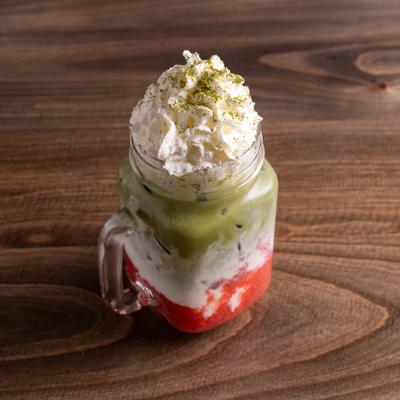 Strawberry matcha latte in a jar with whipped cream.