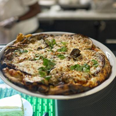 A freshly baked pizza topped with roasted vegetables, mozzarella cheese, and fresh herbs.