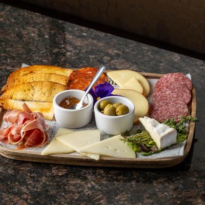 A charcuterie board with sliced meats, cheeses, bread, and olives.