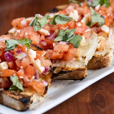 Toasted bread topped with diced tomatoes, cheese, red onions, and fresh basil.