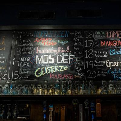 Back bar, beer taps and glasses with a chalkboard menu on the wall above.