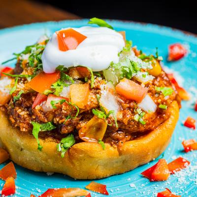 Mexican sope topped with seasoned meat, lettuce, diced tomatoes, and sour cream.