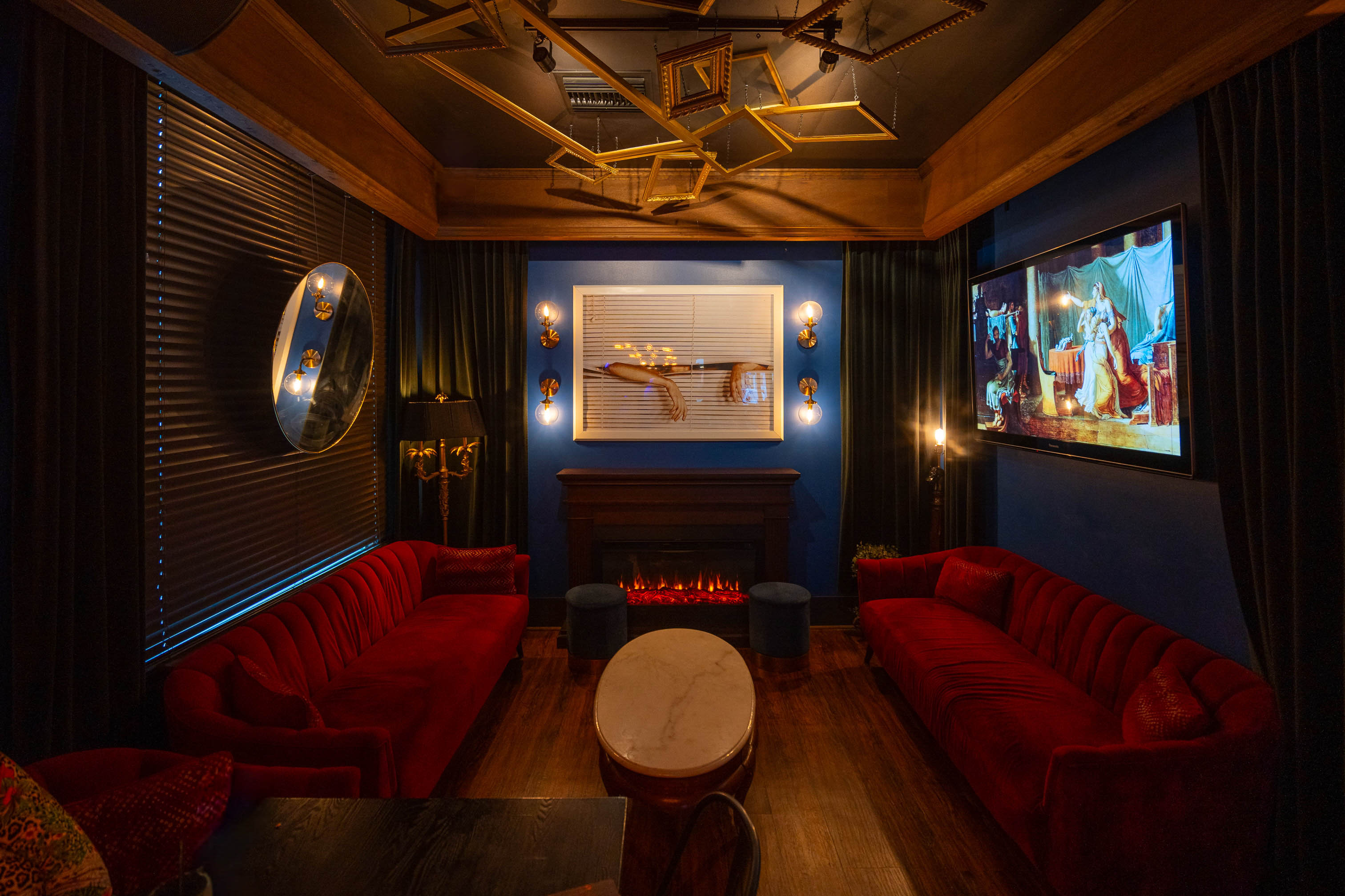 Cozy lounge with red velvet seating beside a fireplace