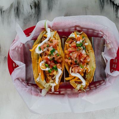 Two fish tacos served in a paper lined basket.