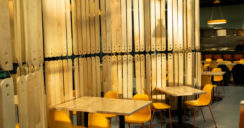 A modern dining area with wooden vertical panels and yellow chairs
