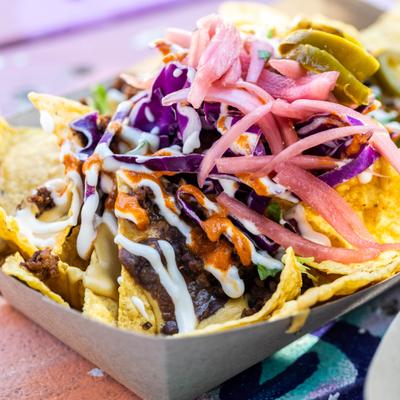 Nachos topped with sauces, melted cheese, red cabbage and pickled onions.