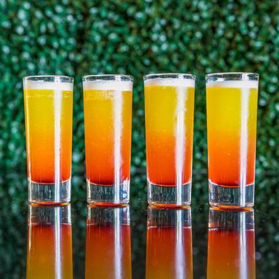 Lined up glasses with an orange cocktail drink.