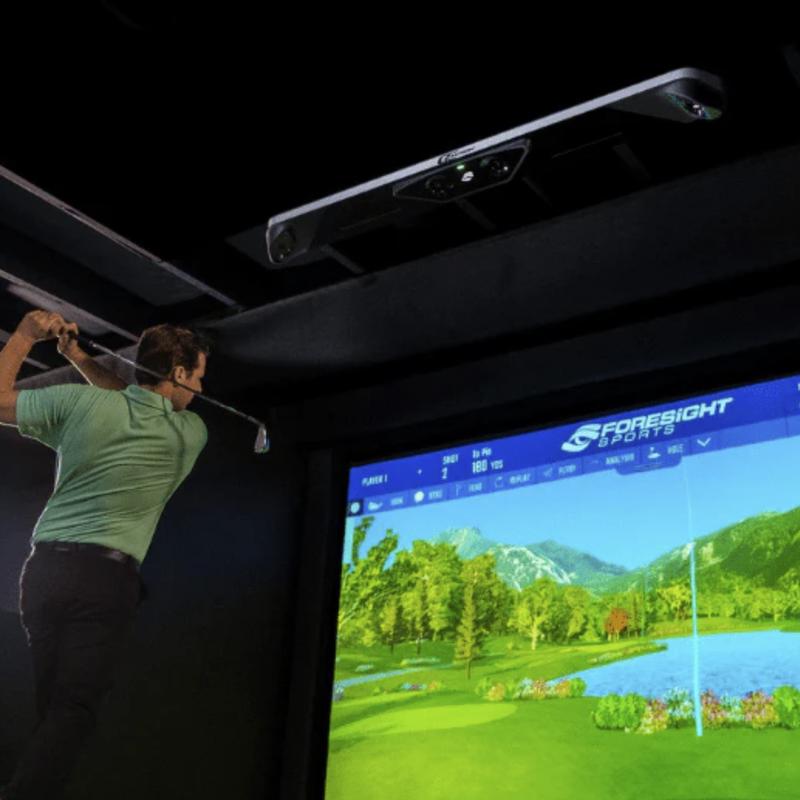 A customer sways a golf club during golf simulator game play