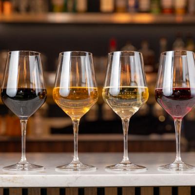 Four glasses of red and white wine on a bar counter.