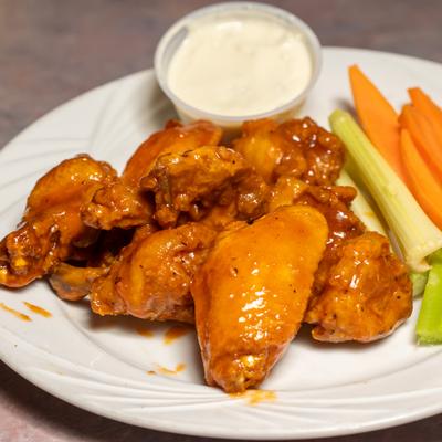 Chicken wings served with celery and carrot sticks with a dipping sauce.