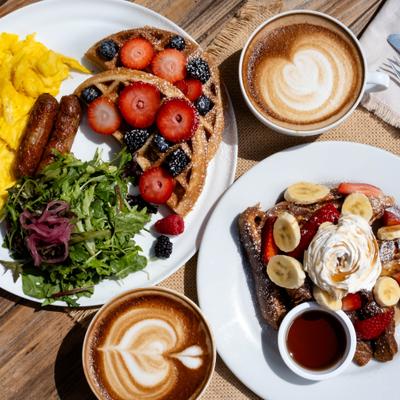 Berry waffles with eggs, sausages, and arugula salad with fruit-topped French toast and lattes.