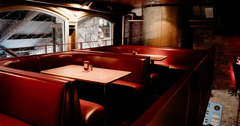 Dimly lit restaurant with two red leather booths and marble tables