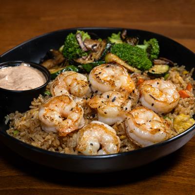 Hibachi shrimp rice bowl with broccoli, mushrooms, zucchini, and a cup of creamy sauce.