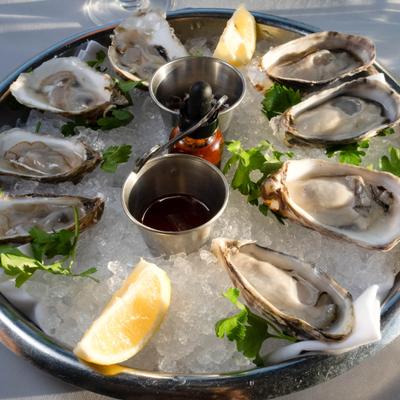 Raw oysters on the half-shell served over ice with lemon wedges and sauces.