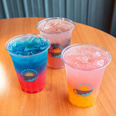 Colorful iced drinks in plastic cups on a table.