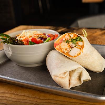 Buffalo chicken wrap with house salad, served, front view.