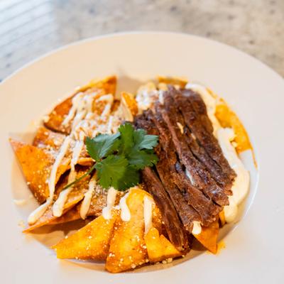Plate of chilaquiles with sliced steak.