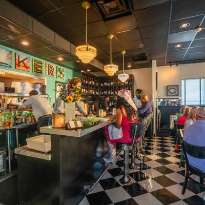 Restaurant interior featuring a bar area with checkered flooring and customers dining.