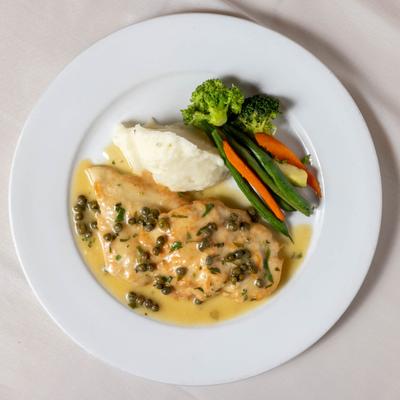 Chicken breast in lemon and caper sauce, served with mashed potatoes and vegetables.