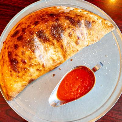 Calzone served with marinara on the side, top view.