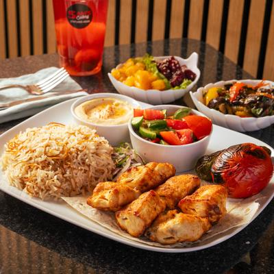 Grilled chicken breast, with salad, rice, and hummus.