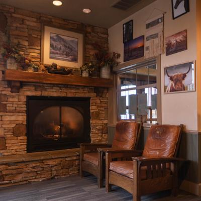 Lounge area with a stone fireplace and two brown leather mission-style chairs.