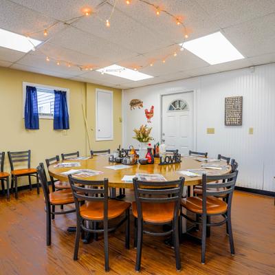 Dining area with a large, round table surrounded by chairs and string lights on the ceiling.