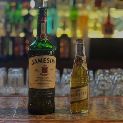 A bottle of Irish whiskey and a bottle of beer on a bar counter.