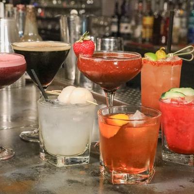 Multiple cocktail drinks placed on bar counter.