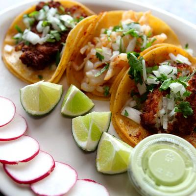 Taco Combo plate with sliced radish, lime wedges and a dipping sauce.