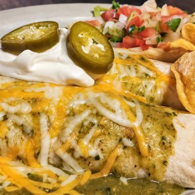 Enchiladas with green sauce, melted cheese, sour cream and jalapenos, with pico and chips..