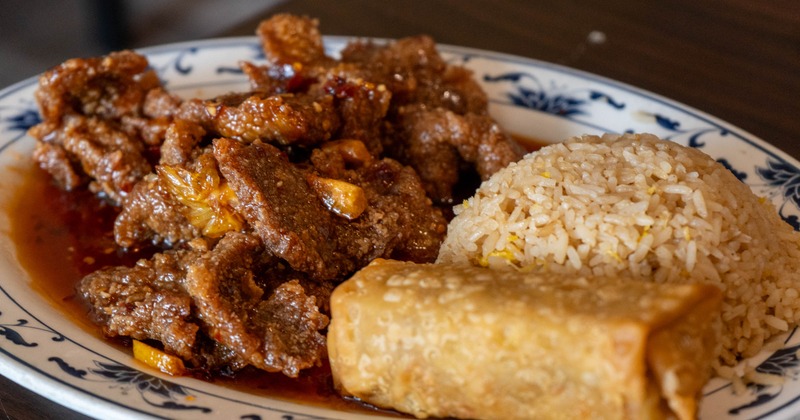 Orange Beef served with rice and a spring roll on the side