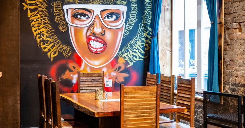 Interior, dining table by a wall decorated with mural art