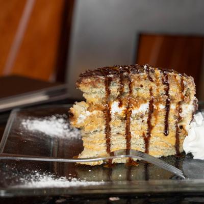Layered cake slice with chocolate drizzle on a plate.