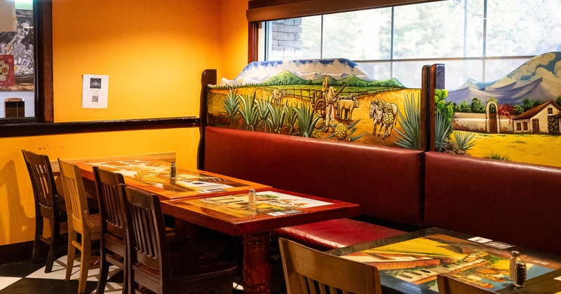Brightly colored restaurant dining area with wooden chairs, murals and checkered floor