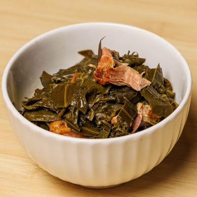 Collard greens with smoked turkey in a white bowl.