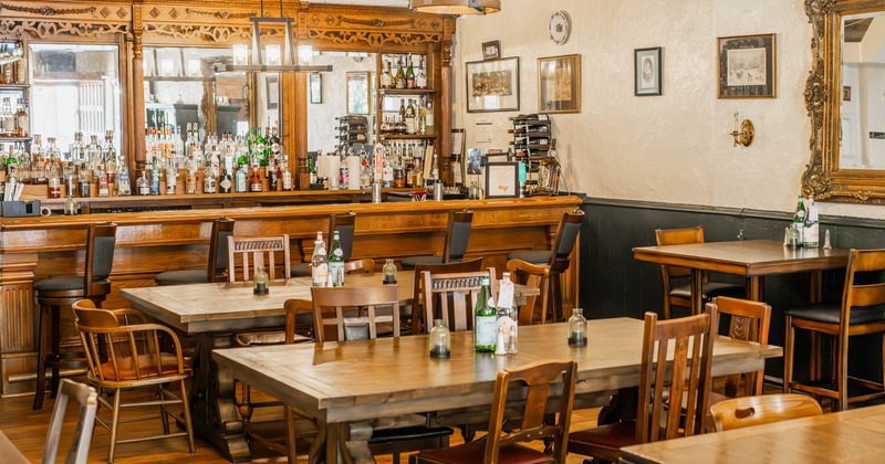 Interior, dining and bar area, wooden tables and chairs, vintage wooden bar with stools