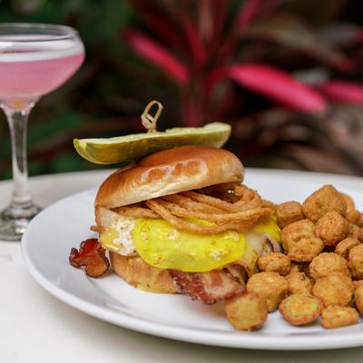 Roasted pork sandwich with bacon, pickled green tomato, fried onions, okra and a cocktail