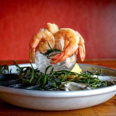 An oyster plate with a glass of shrimp, sauces, and lemon wedges.