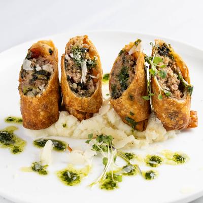 Meat egg rolls served on mashed potatoes.