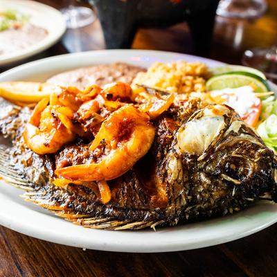 Whole fried fish topped with shrimp, served with rice, beans, and salad.
